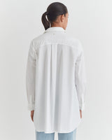 A person standing with their back to the camera, wearing a long-sleeved shirt and jeans.