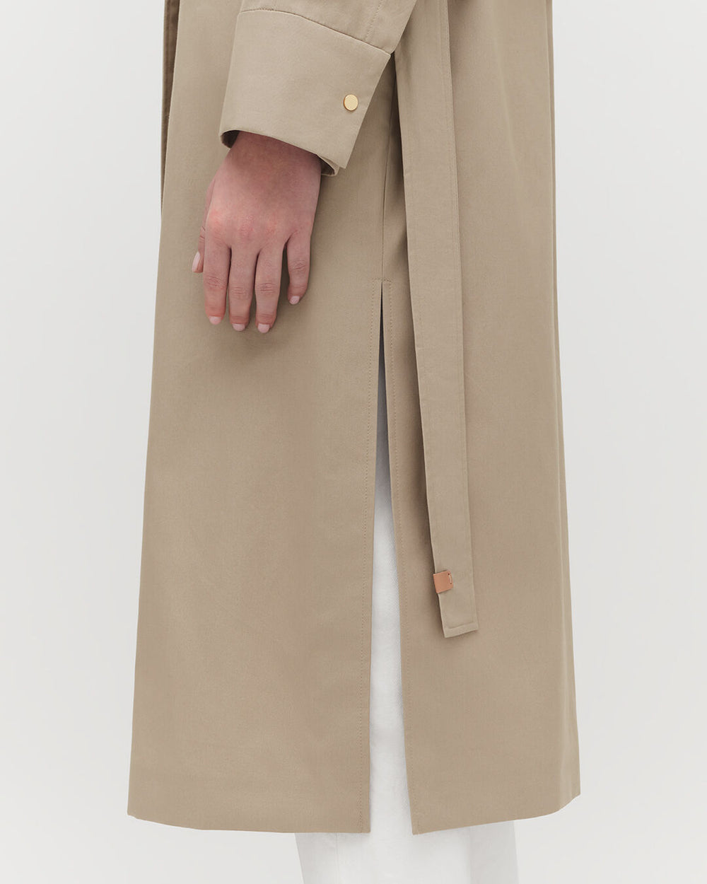Close-up of a person wearing a long coat with hand visible.