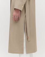 Close-up of a person wearing a long coat with hand visible.