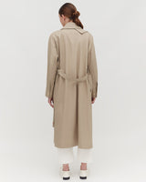 Woman facing away wearing a trench coat and pants, with a belt tied at the back.