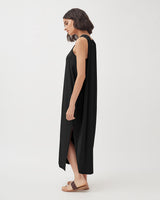 Woman walking in a sleeveless long dress with sandals.
