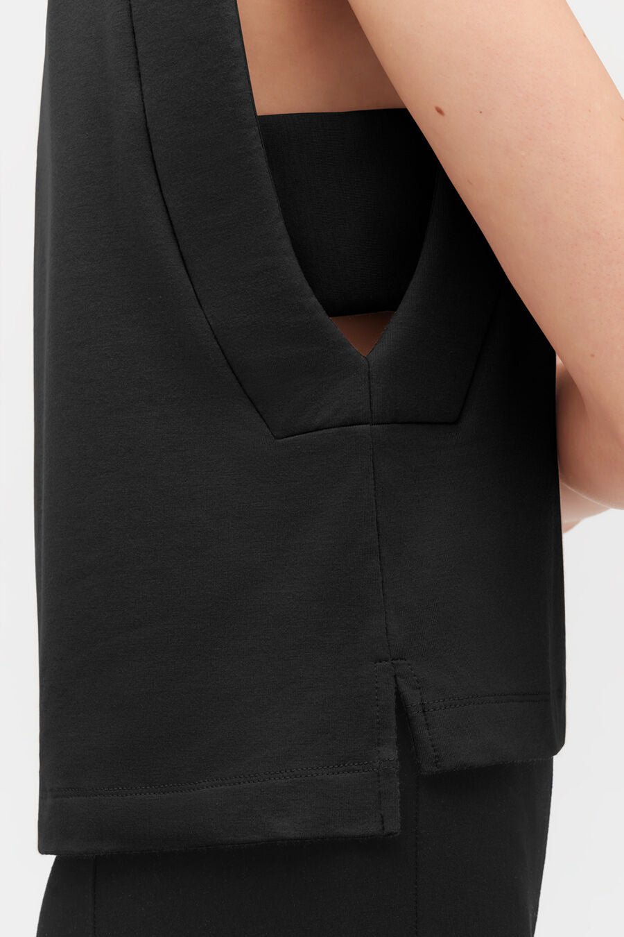 Close-up of a person wearing a sleeveless top with a V-neckline.