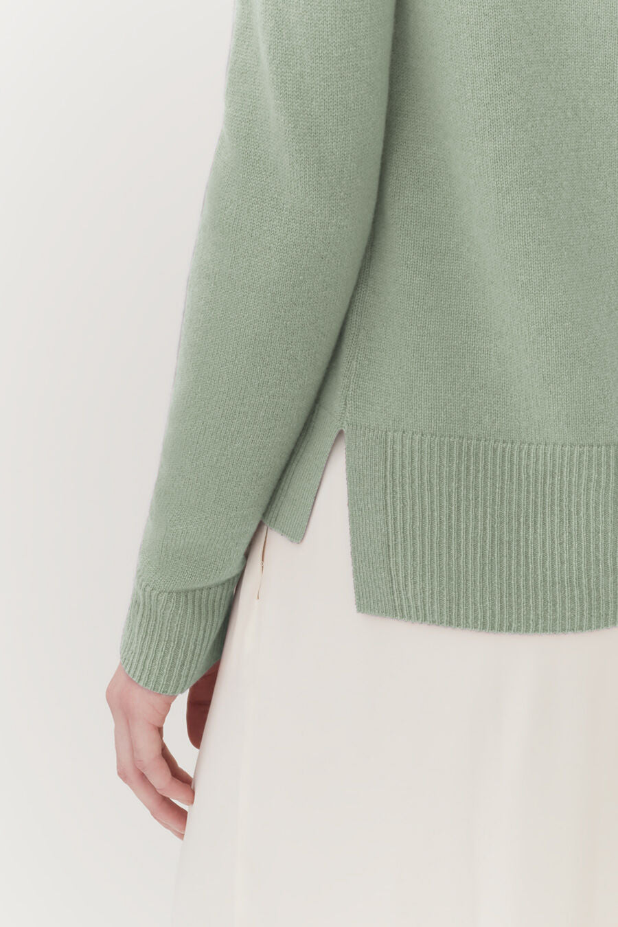 Close-up of a person wearing a sweater and skirt, focusing on the side view.