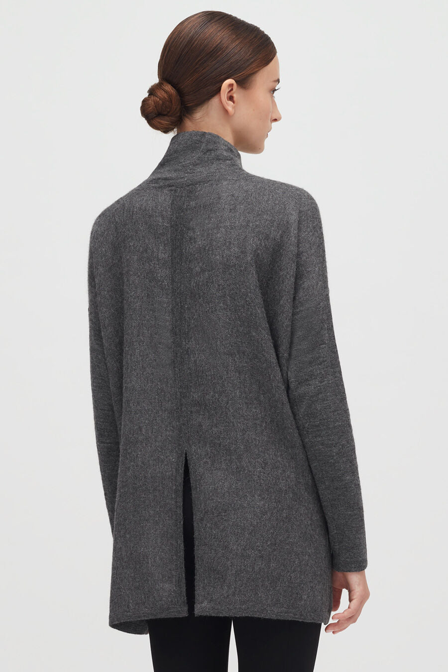 Woman in a jacket viewed from back, with a bun hairstyle.