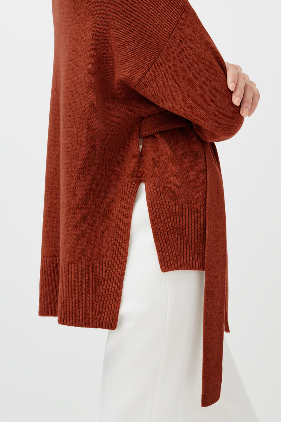 Person adjusting a sweater tied around their waist.