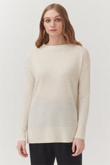 Woman standing in a long sleeve top and trousers.