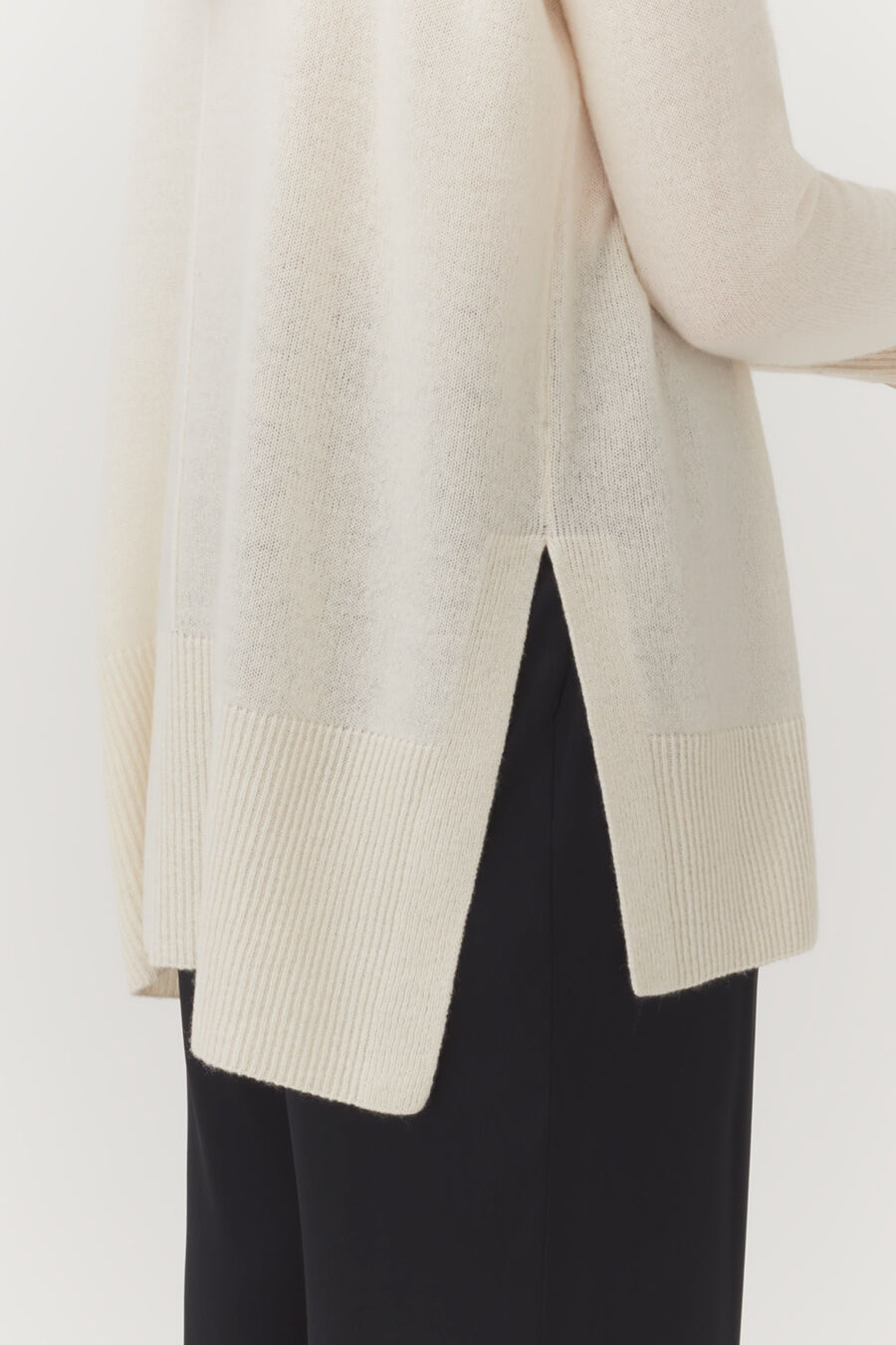 Person wearing an open cardigan and pants.