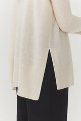 Person wearing an open cardigan and pants.