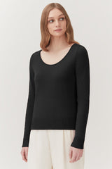 Woman wearing a sweater and pants standing in a neutral pose.