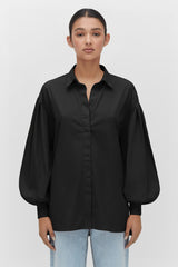 Woman in a buttoned shirt and jeans standing straight