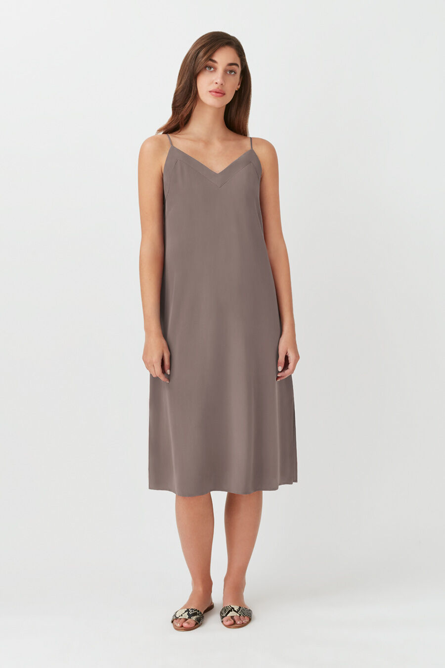 Person standing in a sleeveless knee-length dress and sandals.