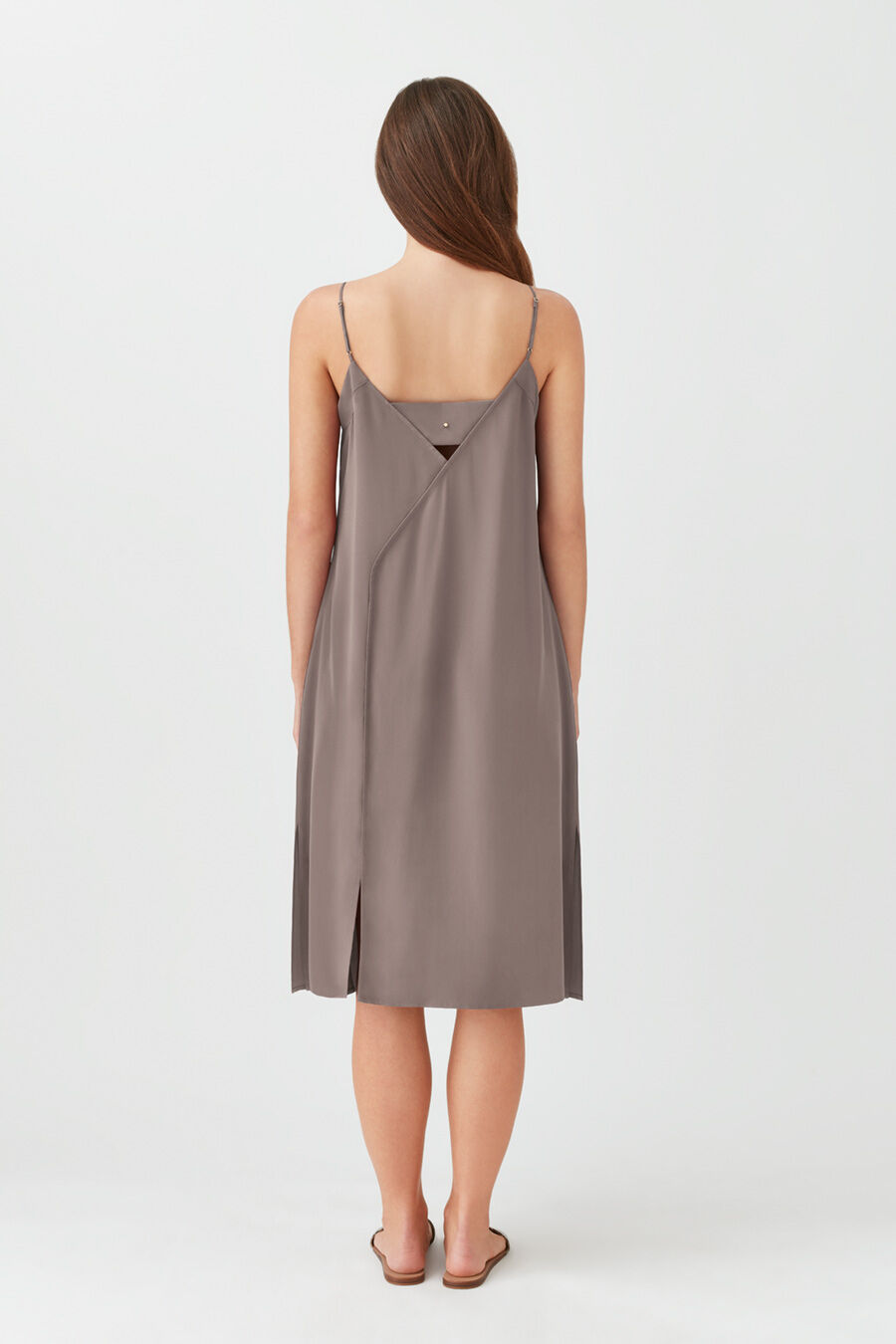 Woman viewed from back wearing a knee-length dress, standing against a plain background.