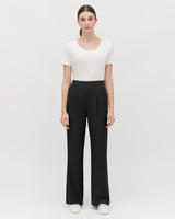Woman standing in a T-shirt and trousers, facing forward.