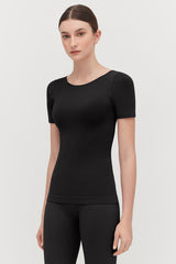 Woman standing in a studio wearing a fitted top and leggings.