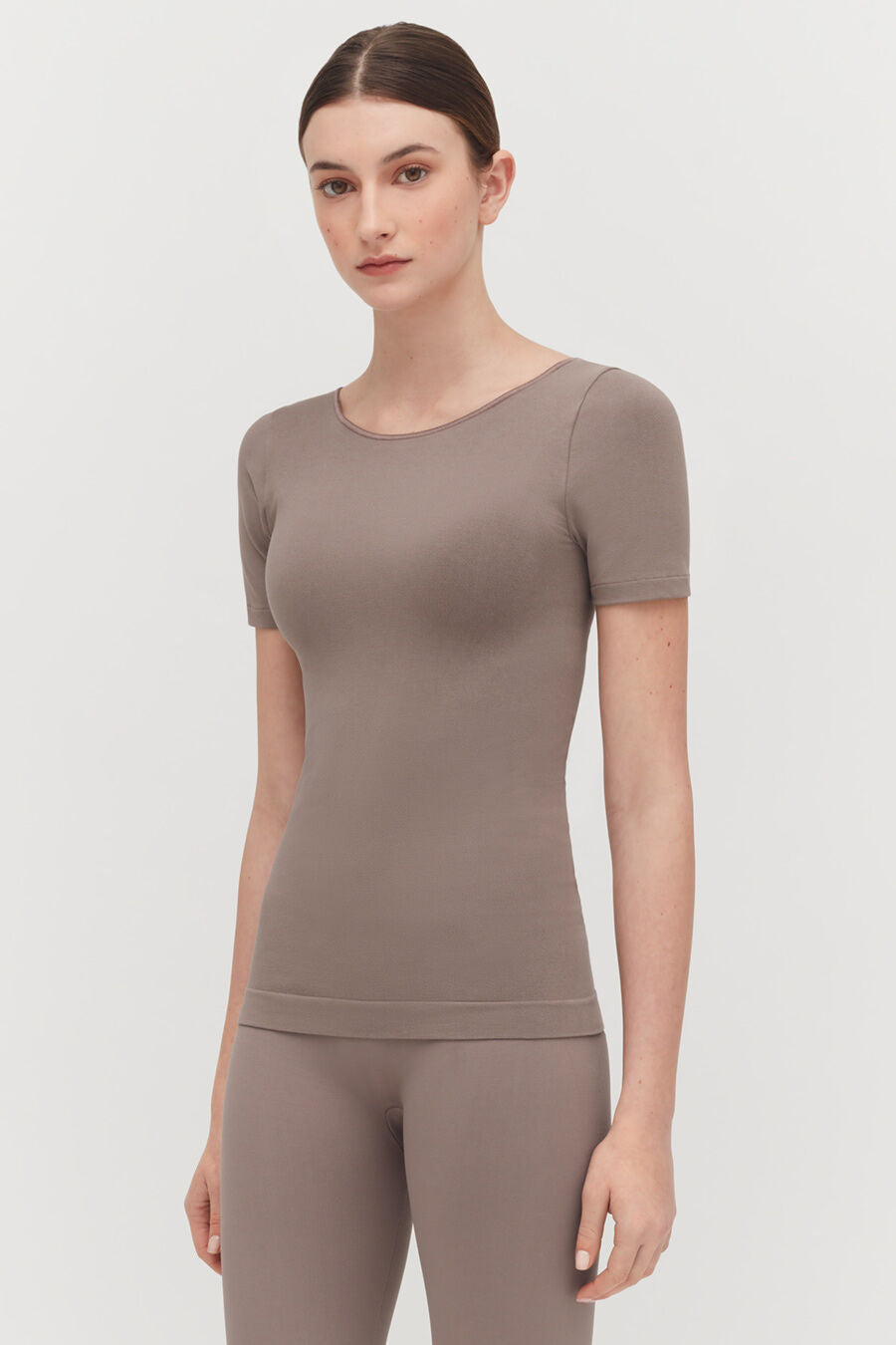 Woman standing in a short-sleeved top and leggings, looking at camera.