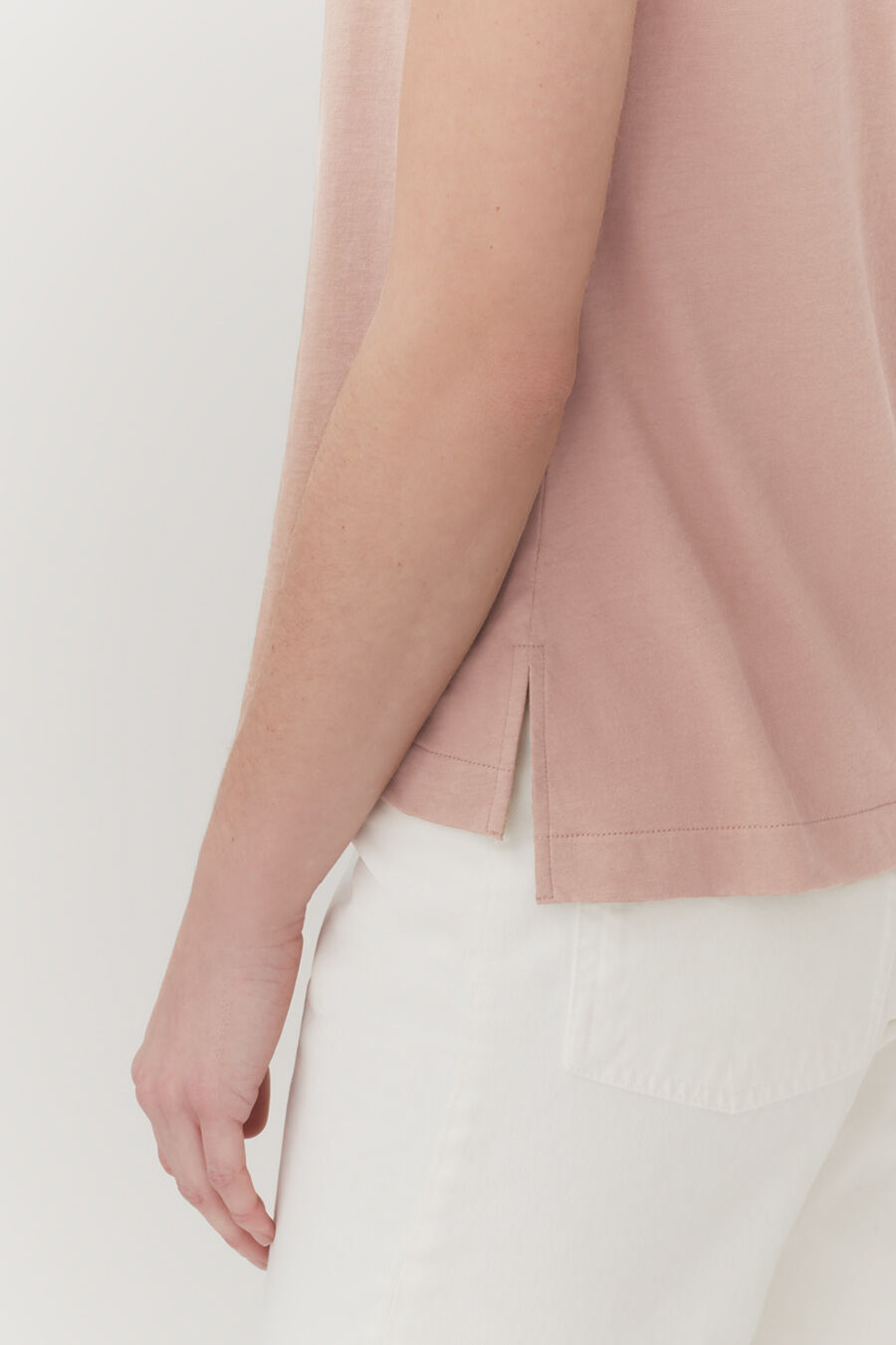 Close-up of a person standing, showing only their arm and side.