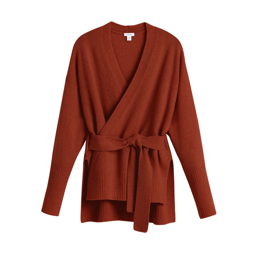 Sweater with a wrap design and belt on a plain background.