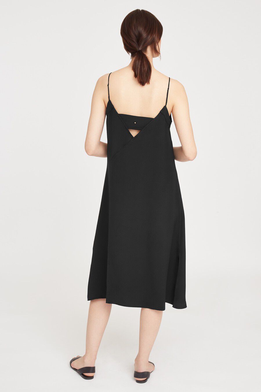 Woman in a mid-length dress and sandals, viewed from the back.