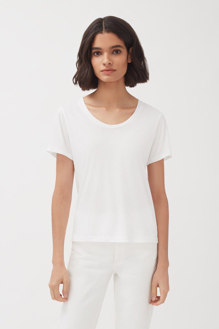 Woman standing wearing a T-shirt and pants, looking at the camera.